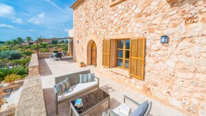 Un bâtiment en pierre doté d’un patio aménagé avec du mobilier d’extérieur et offrant une vue sur le paysage environnant.