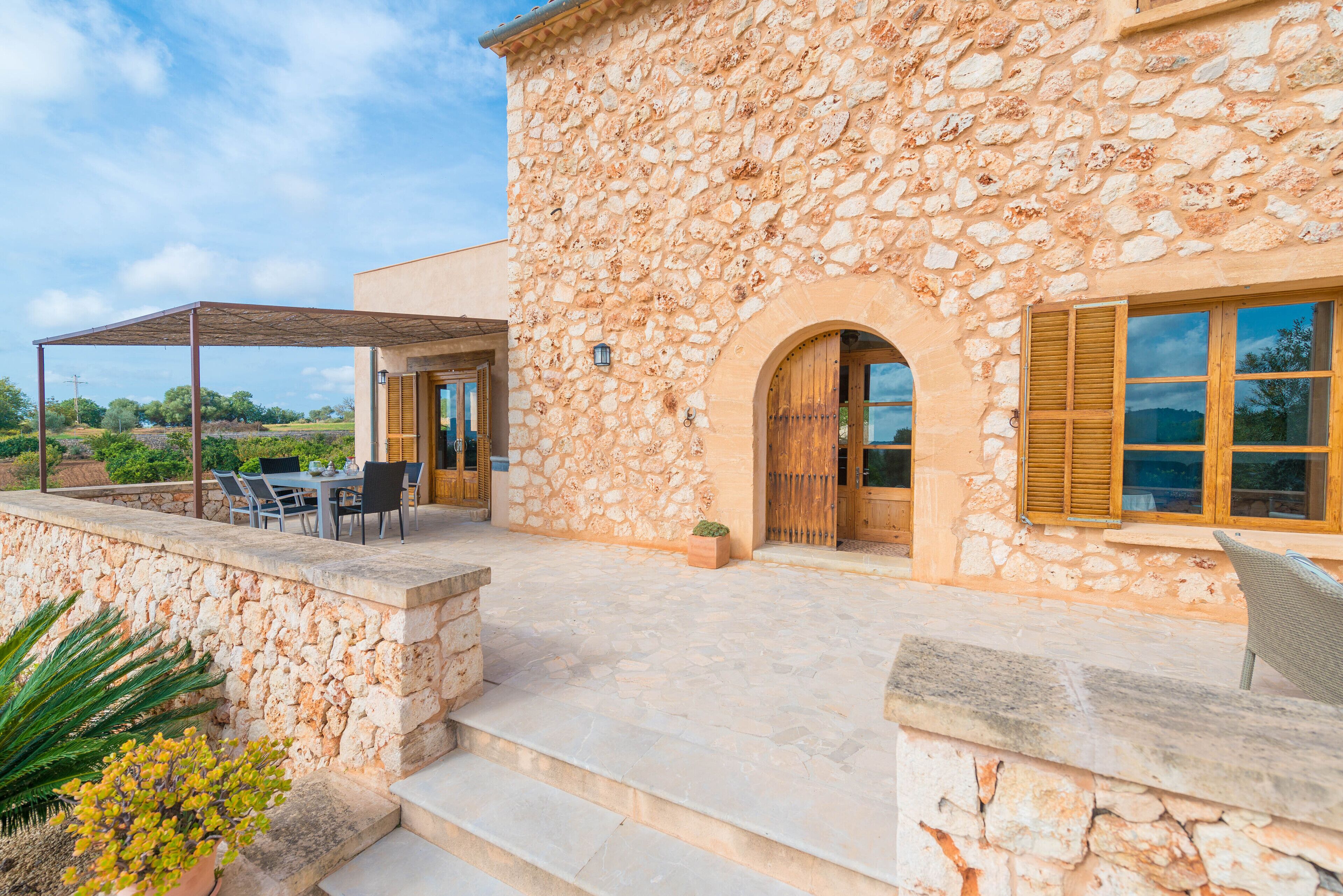 A stone building with a covered patio, outdoor seating, and a view of the countryside.