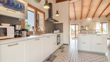 A modern kitchen with white cabinets, a built-in oven, and a coffee maker.