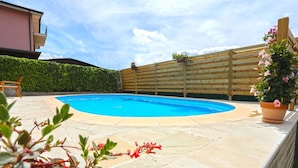 En swimmingpool med et træhegn og krukker med planter.