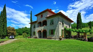 A stone house with a red-tiled roof, green shutters, and a well-maintained lawn. - Villa Lo Scoiattolo - Holiday Country Villa with private swimming pool in Casentino Valley, Tuscany (Subbiano)