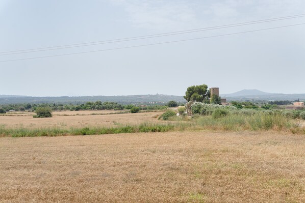Paisaje rural con un campo, una torre y colinas a lo lejos.