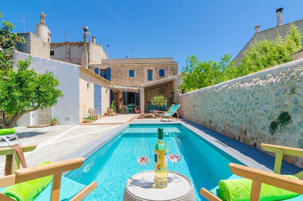 A swimming pool with lounge chairs and a bottle of wine on a table.