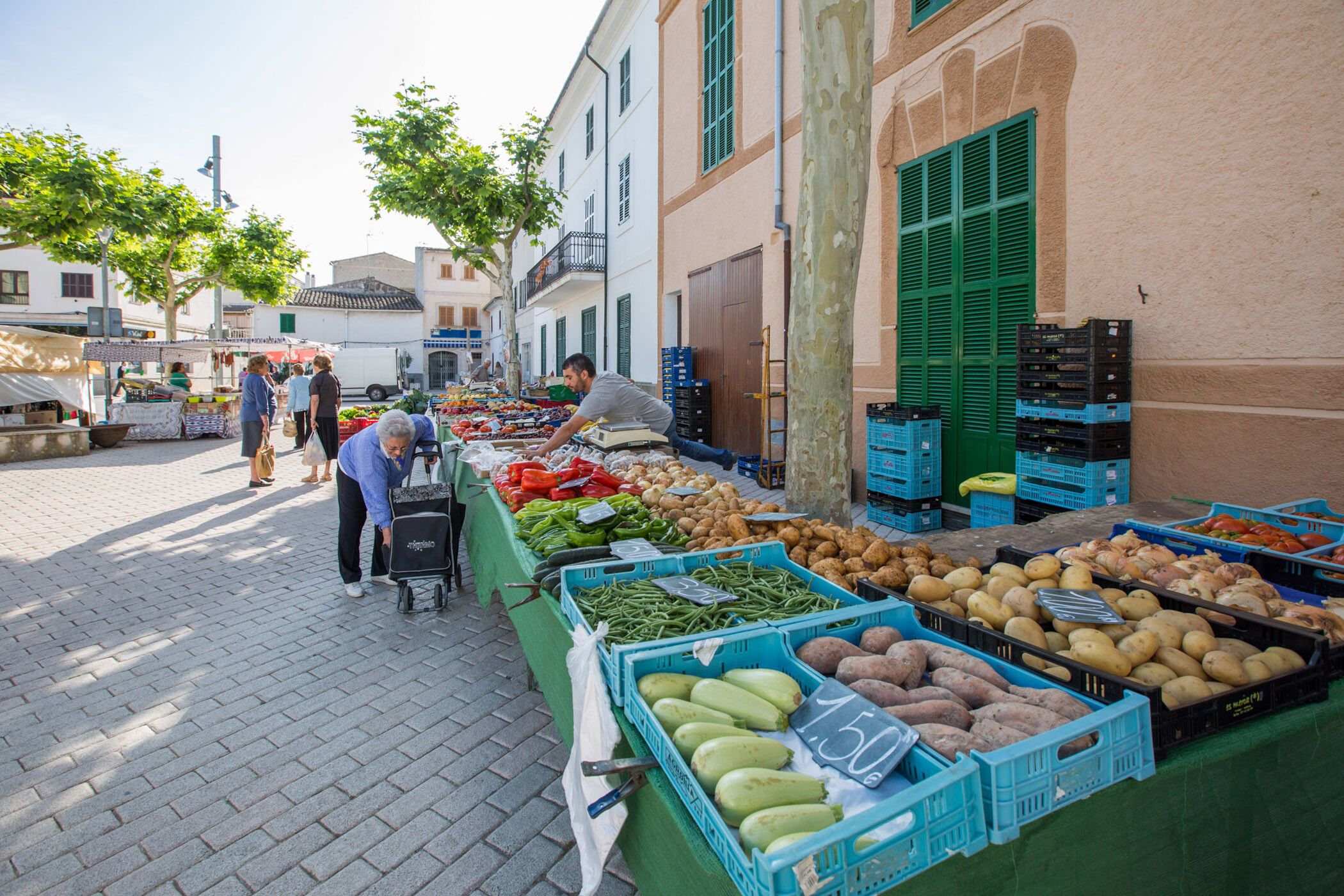 A bustling outdoor market with various fresh produce displayed in crates.