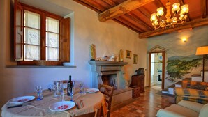 Un coin repas avec une table dressée pour quatre personnes, une cheminée et un salon avec un canapé et une fresque murale.