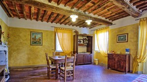Una habitación con techo de madera, una mesa de comedor con sillas, una cama y un armario con espejo.