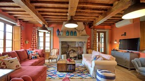 A cozy living room with a fireplace, wooden beams, and a television.