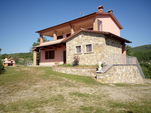 Une maison à deux étages avec une façade en pierre et une couleur rose.