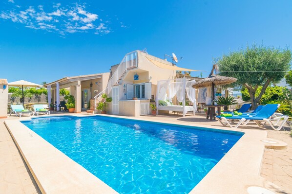 A swimming pool with lounge chairs and a building with a balcony.