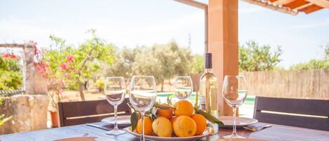 Una mesa lista para una comida, con un plato de naranjas, copas de vino y una botella.