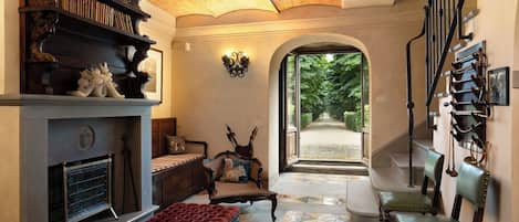 Un interior tradicional con chimenea, zona de estar y una escalera que da a un jardín.