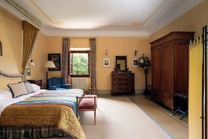 Ein Schlafzimmer mit einem großen Bett, einem Schminktisch, einem Sessel und einem Kleiderschrank.