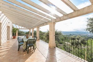 A covered outdoor patio with a table and chairs, overlooking a scenic landscape.