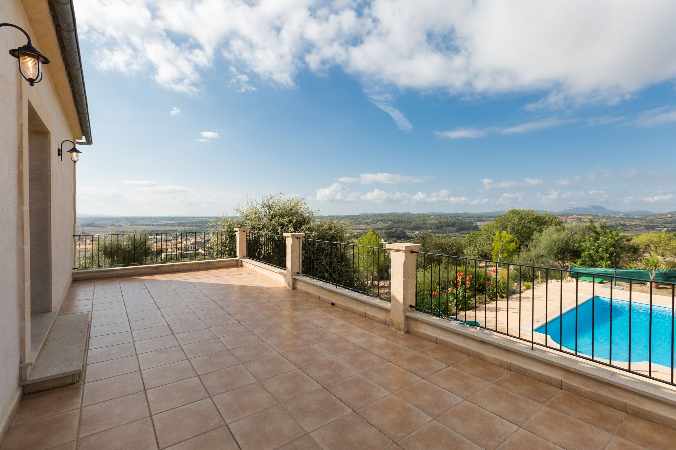 Un balcon avec un sol carrelé, une piscine et une vue sur la campagne.