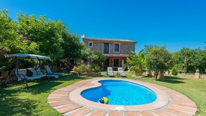 A swimming pool with a stone border, surrounded by a well-maintained lawn and a house with a tiled roof. - FINCA CAN DIEGO - Villa with private pool in Inca. Free WiFi (Inca)