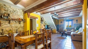 A dining area with a wooden table and chairs, a stone wall, and a yellow accent wall. - FINCA CAN DIEGO - Villa with private pool in Inca. Free WiFi (Inca)