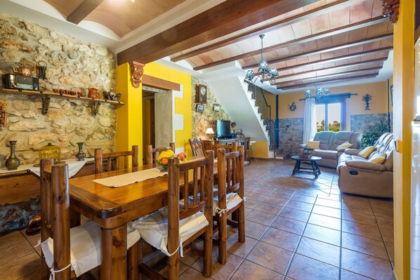 A dining area with a wooden table and chairs, a stone wall, and a yellow accent wall.