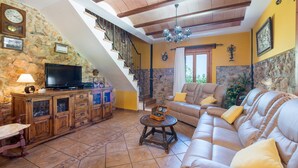 A spacious living room with a stone wall, wooden staircase, and a comfortable sofa. - FINCA CAN DIEGO - Villa with private pool in Inca. Free WiFi (Inca)
