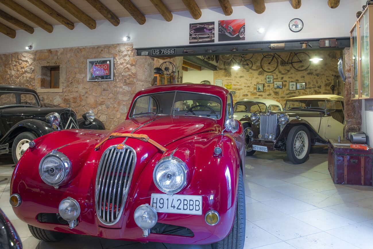 A vintage car exhibition with a red car prominently displayed in the foreground.