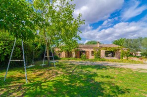 Une maison avec un jardin, comprenant une balançoire et un banc.