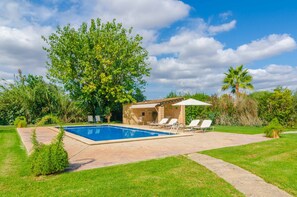 Une piscine avec des chaises longues et un petit bâtiment doté d’une terrasse.