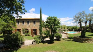 Ein Steinhaus mit Pool und gepflegtem Rasen.