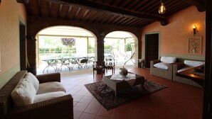 Ein gemütliches Interieur mit hohen Decken, Kamin und einer Sitzecke mit Sofa und Sesseln.
