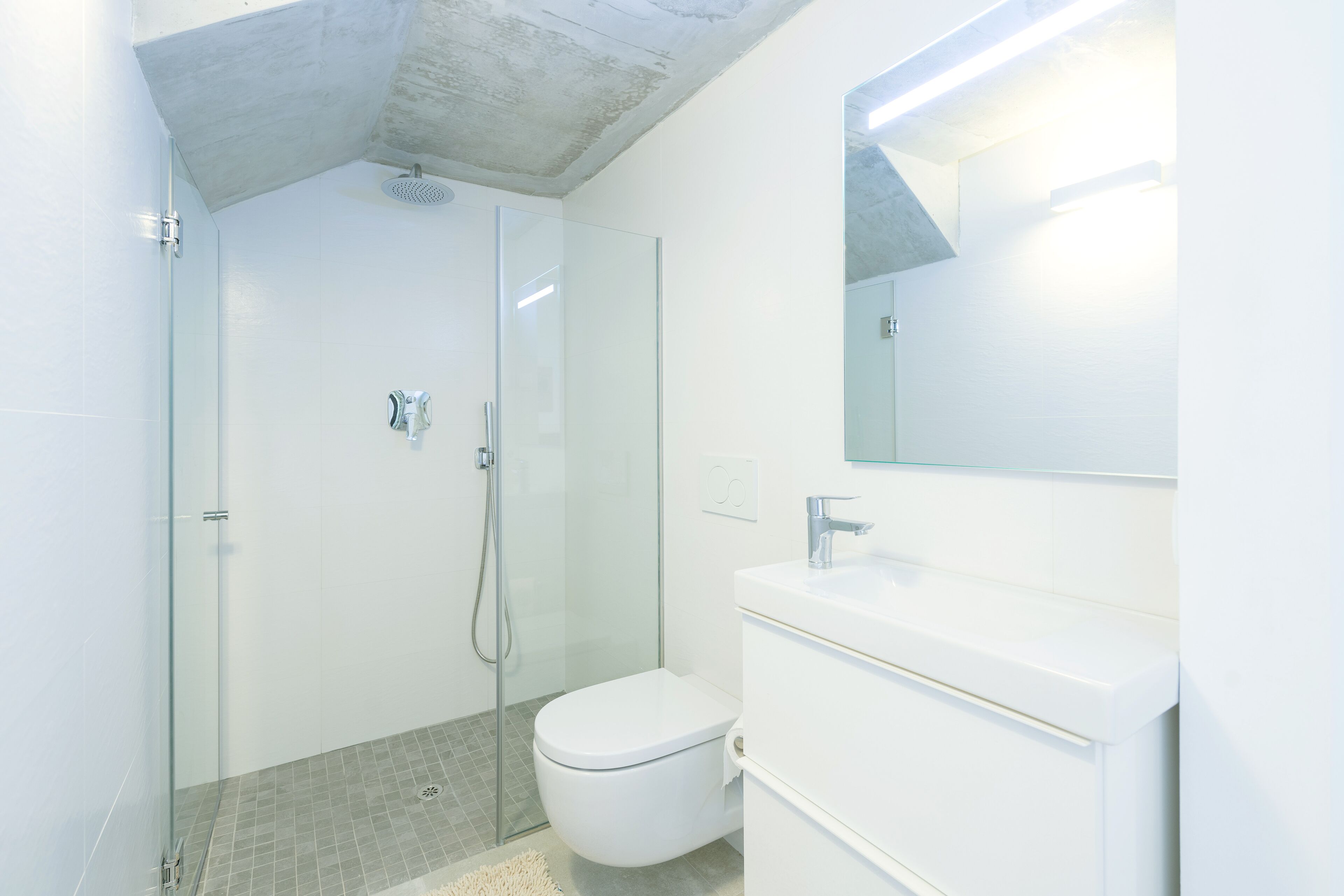 A modern bathroom with a glass-enclosed shower, a white toilet, and a vanity with a mirror.