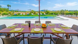 A dining table set for six with a pool view, outdoor umbrellas, and a clear sky. - CAN GUSTI - Villa with private pool in Manacor. Free WiFi. (Manacor)
