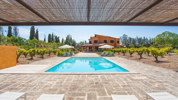 A swimming pool with lounge chairs and umbrellas, surrounded by a stone patio and a building in the background. - FINCA CAN POL - Villa with private pool in Inca. Free WiFi (inca)