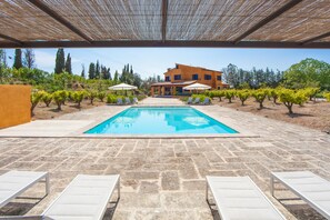 A swimming pool with lounge chairs and umbrellas, surrounded by a stone patio and a building in the background. - FINCA CAN POL - Villa with private pool in Inca. Free WiFi (inca)