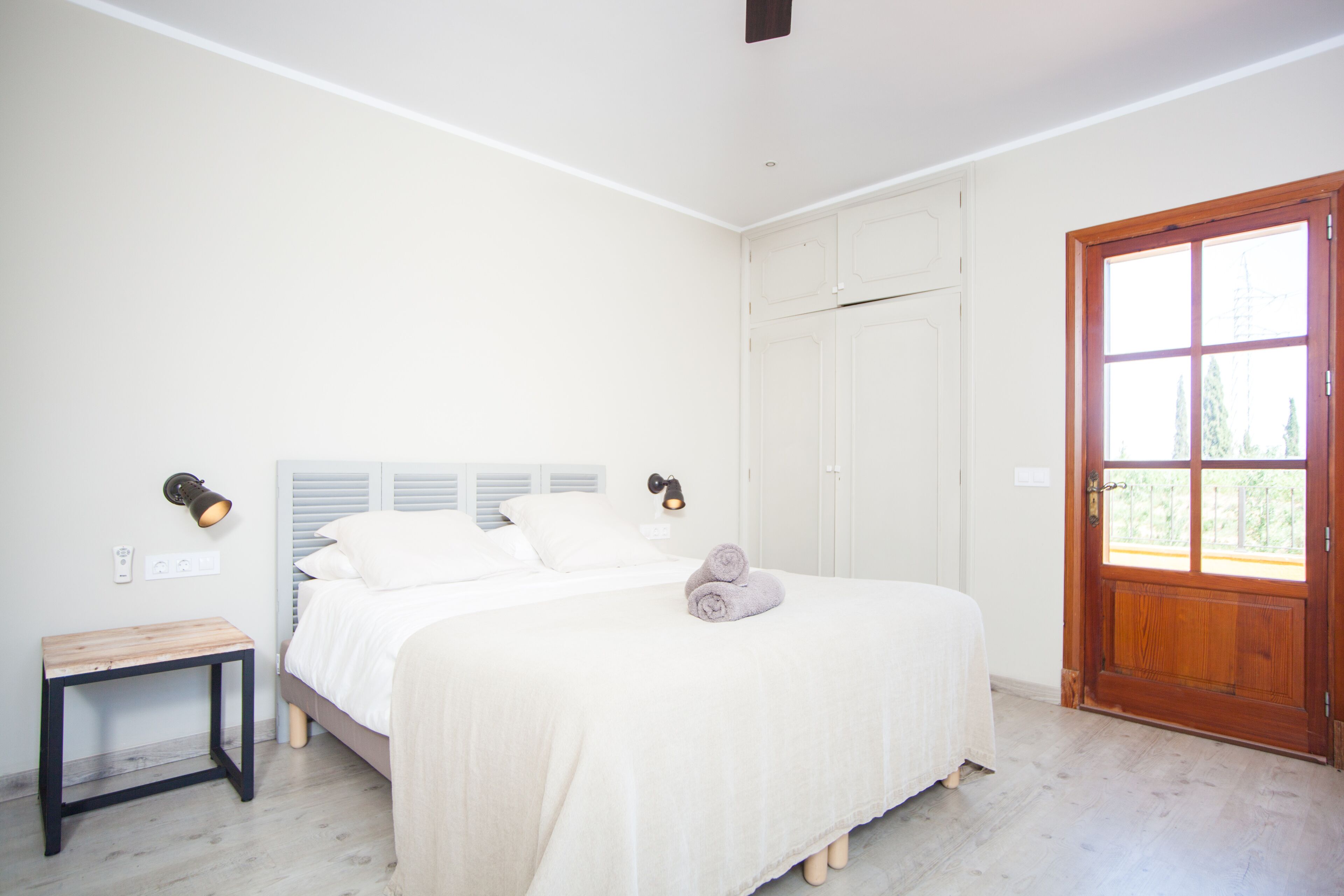 A bedroom with a bed, bedside table, and a door leading to a balcony.