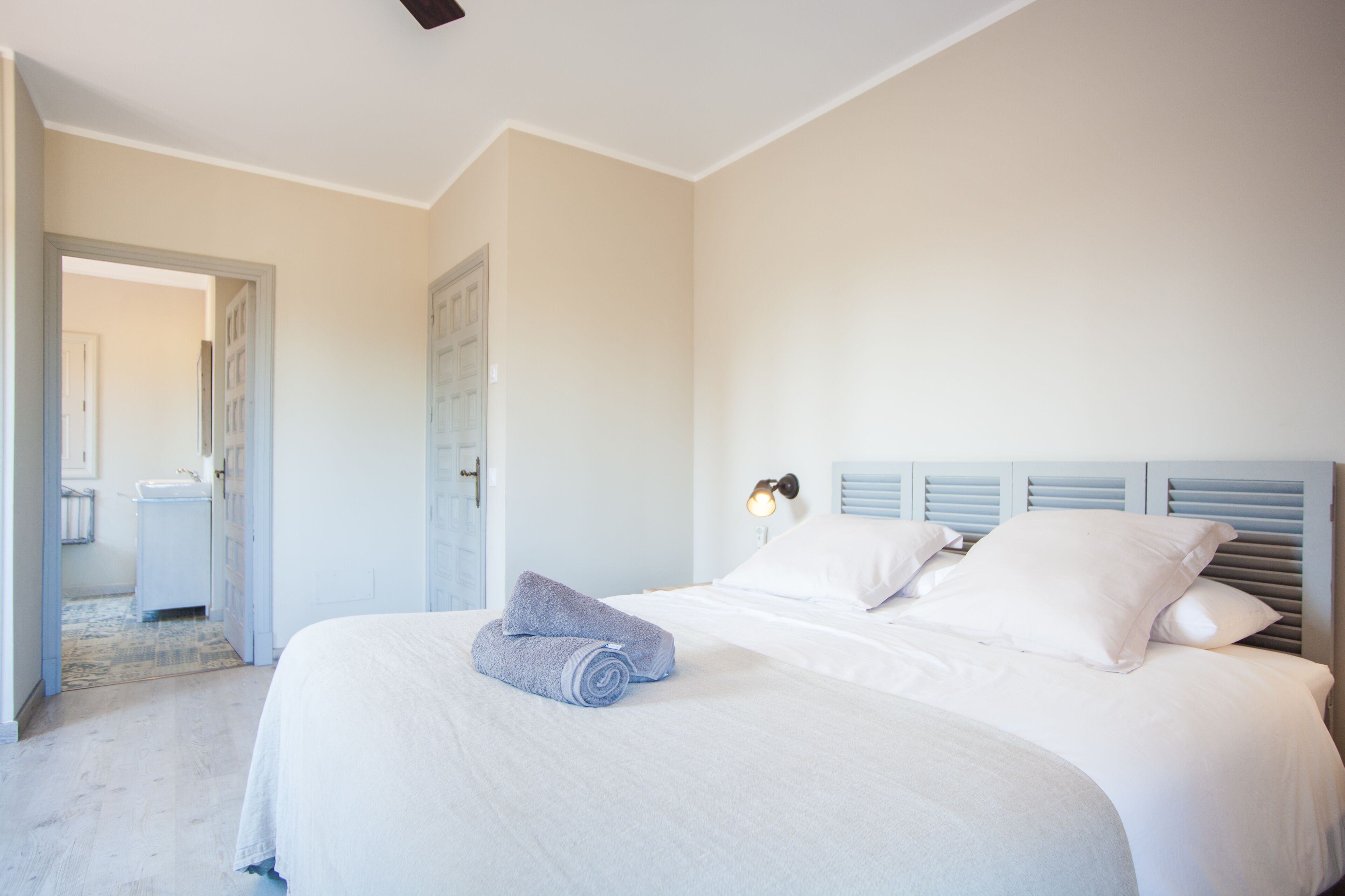 Een slaapkamer met een bed, een nachtkastje en een deur naar een andere kamer.