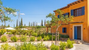 A two-story building with a yellow facade and blue shutters, surrounded by a landscaped garden with various shrubs and trees. - FINCA CAN POL - Villa with private pool in Inca. Free WiFi (inca)