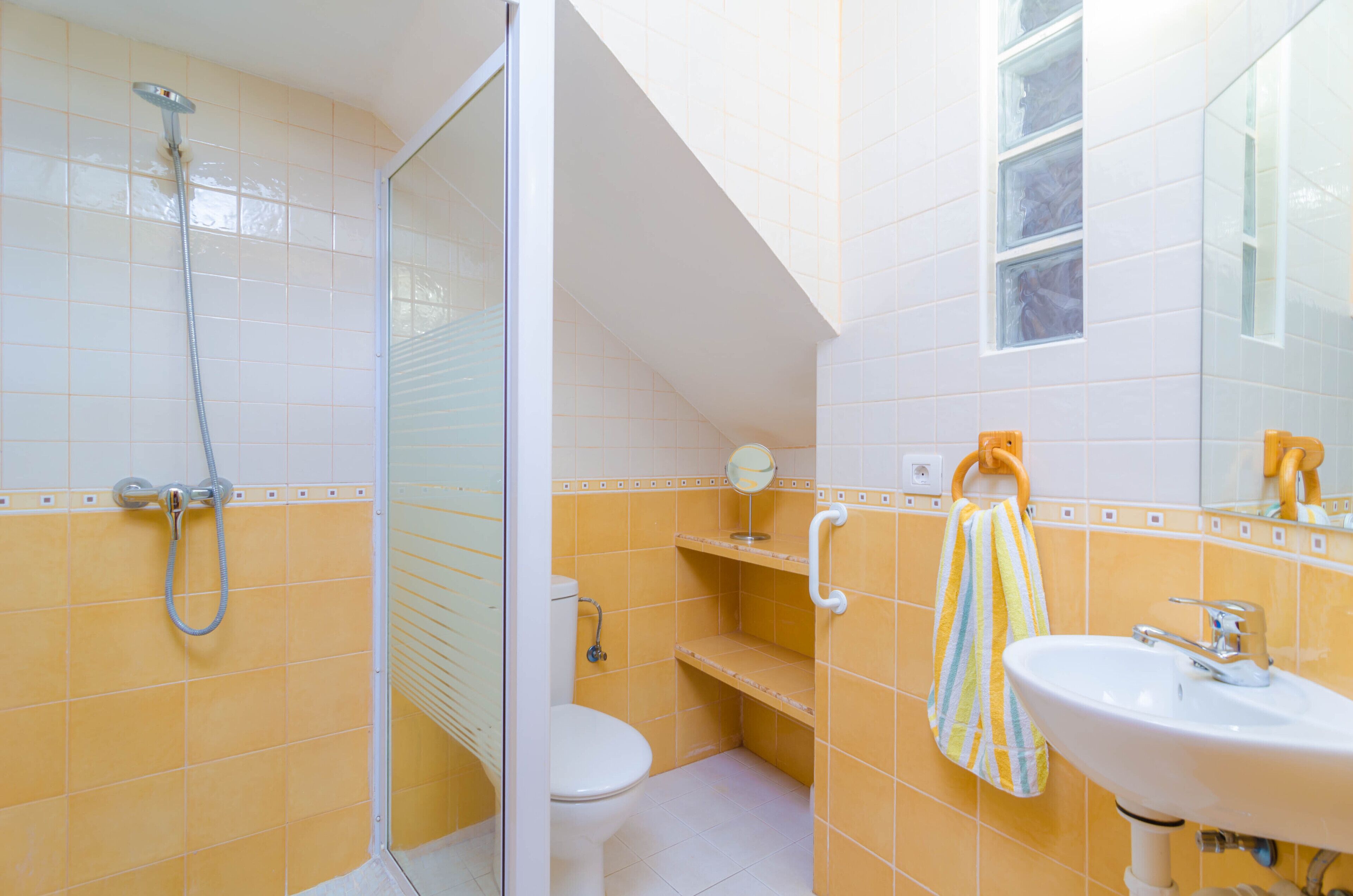 A bathroom with a shower, toilet, sink, and a mirror.