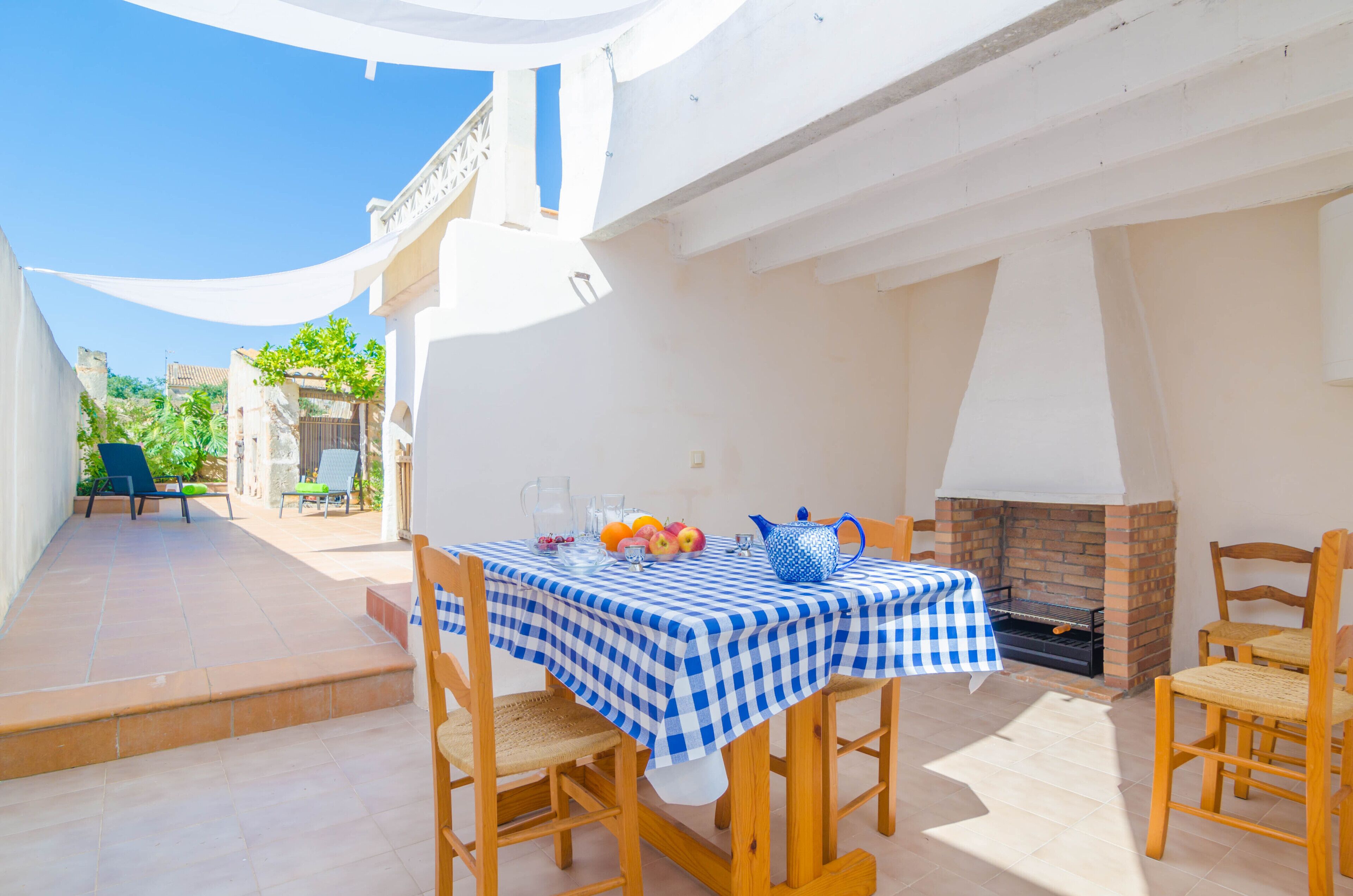 A patio with a checkered tablecloth, a brick fireplace, and outdoor seating.