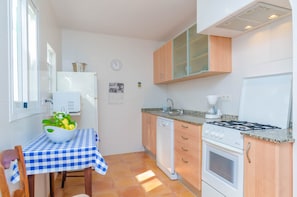 A compact kitchen with a checkered tablecloth, a sink, a stove, and wooden cabinets.