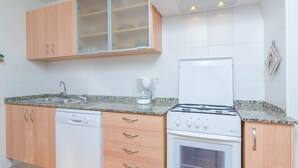 A compact kitchen with a dishwasher, stove, and a coffee maker.