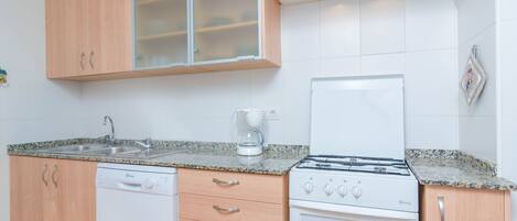 A compact kitchen with a dishwasher, stove, and a coffee maker.