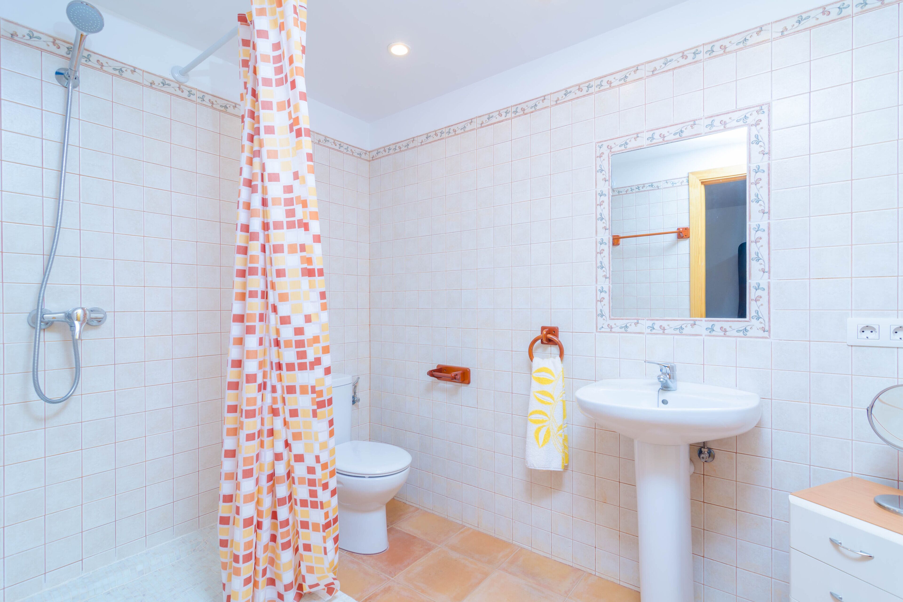 A bathroom with a shower, toilet, sink, and a mirror.