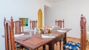 A dining table set with plates, glasses, and a fruit basket.
