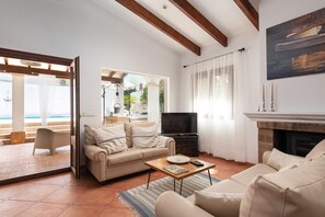 Una sala de estar con sofá, mesa de centro, chimenea y televisor.