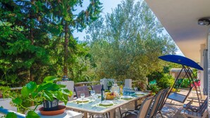 An outdoor dining area with a table set for four, surrounded by chairs, and a blue umbrella providing shade. - VILLA GARBA - Villa with private pool in Felanitx. Free WIFI (Felanitx)