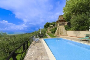 A swimming pool with a stone deck, a stone wall, and a view of the landscape.