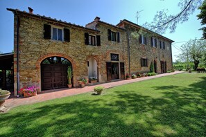 Un edificio de piedra con varias puertas y ventanas, un camino pavimentado y un césped bien cuidado.