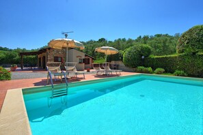 A swimming pool with lounge chairs and umbrellas, surrounded by a stone building with a garden. - Beautiful private villa for 6 people with A/C, WIFI, private pool, TV and panoramic view (La California)