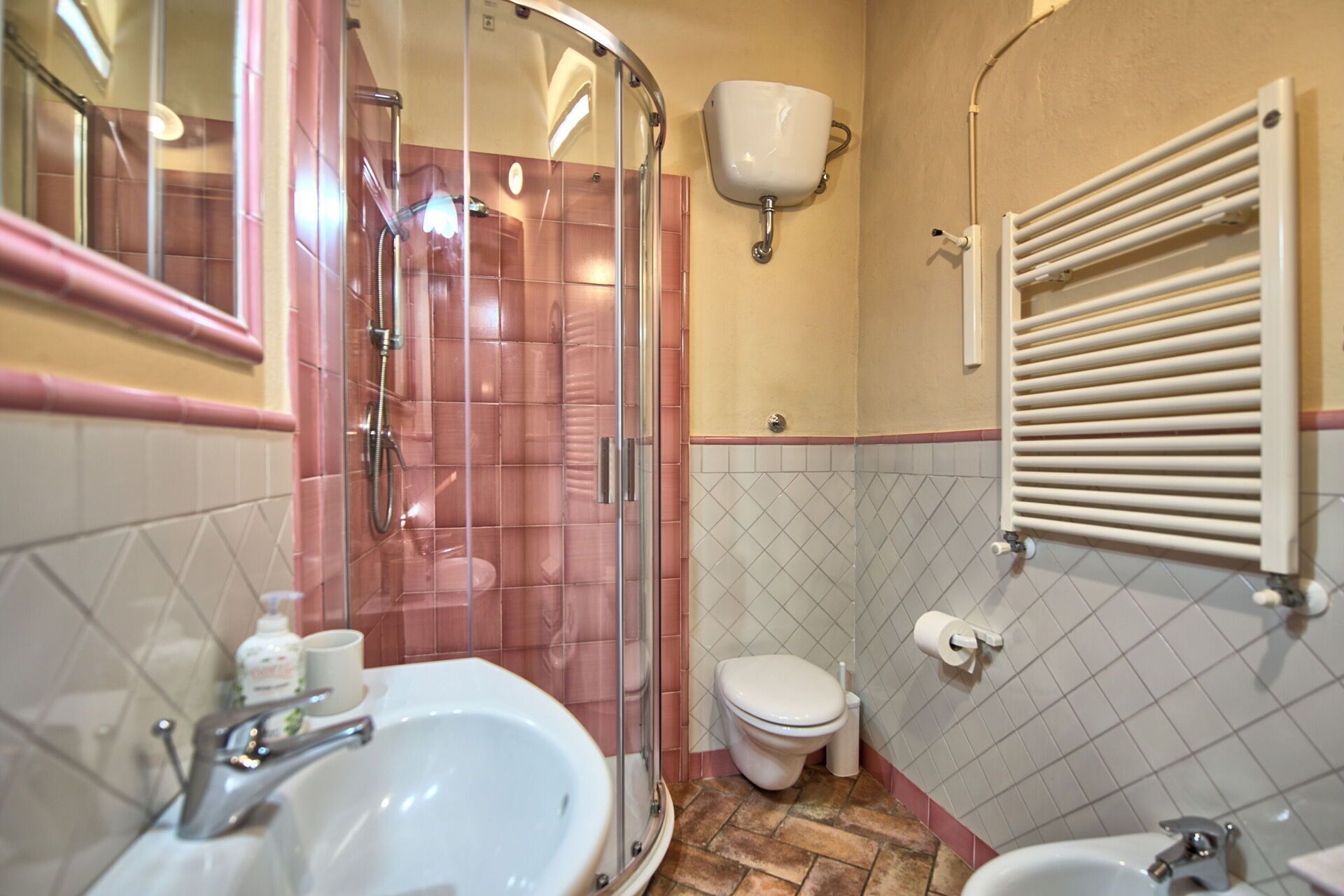 A bathroom with a glass-enclosed shower, a sink, a toilet, and a towel rack.