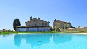 Un grand bâtiment en pierre avec une piscine devant.