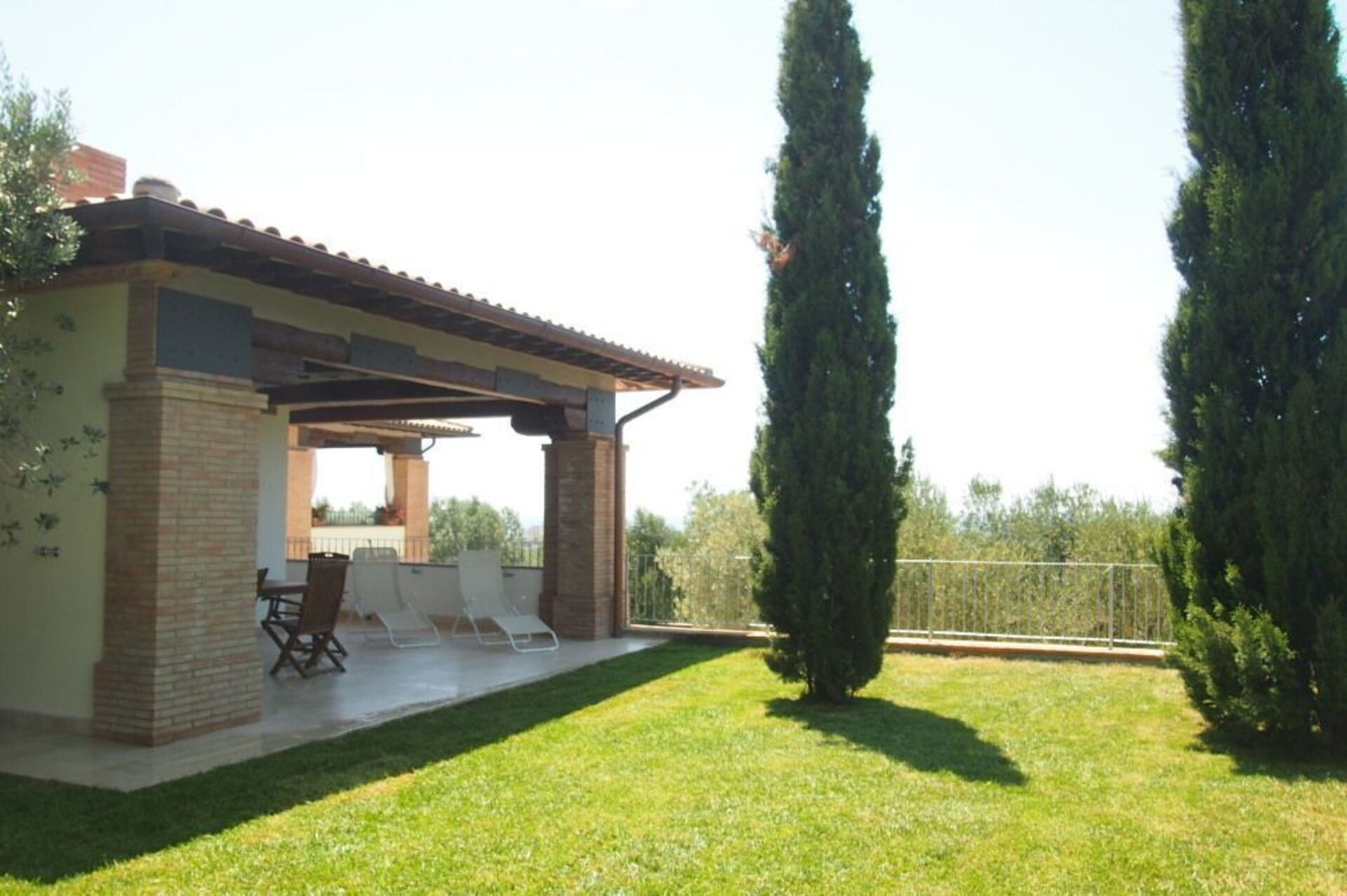 Un patio techado con mobiliario exterior y un césped bien cuidado.