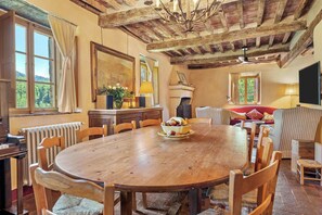 A dining area with a wooden table, chairs, a fireplace, and a sofa.